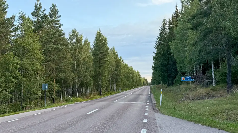 E45 norr ut genom byn Vattnäs vid kommungränsen till Orsa, med skog på båda sidor av vägen. Bild.