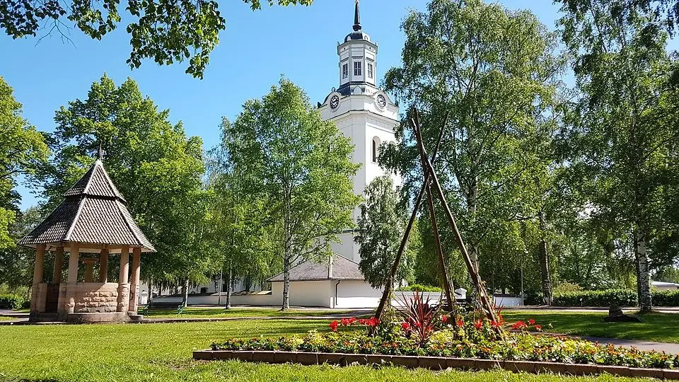 Tingshusparken i sommarskrud med Orsa kyrka i bakgrunden.,