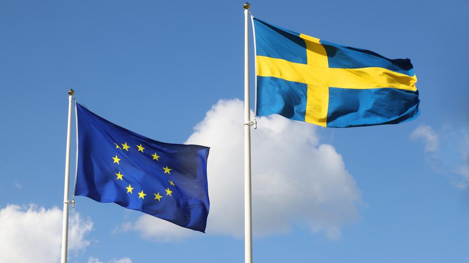EU-flaggan vajar tillsammans med den svenska flaggan mot en blå himmel. Foto.