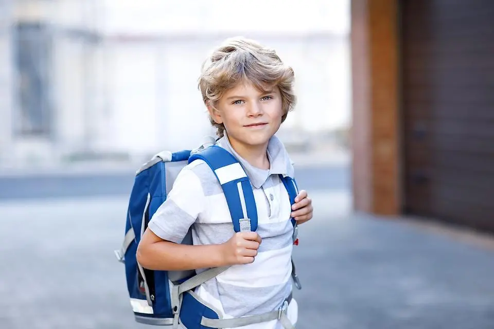 Liten pojke är på väg till skolan efter sommarlovet. Han har en ryggsäck.