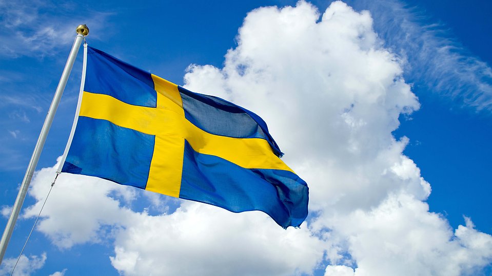 Sveriges flagga mot blå himmel med lite vita moln
