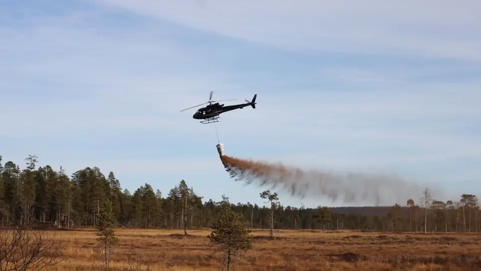Helikopter som släpper ut kalk över en våtmark eller sjö
