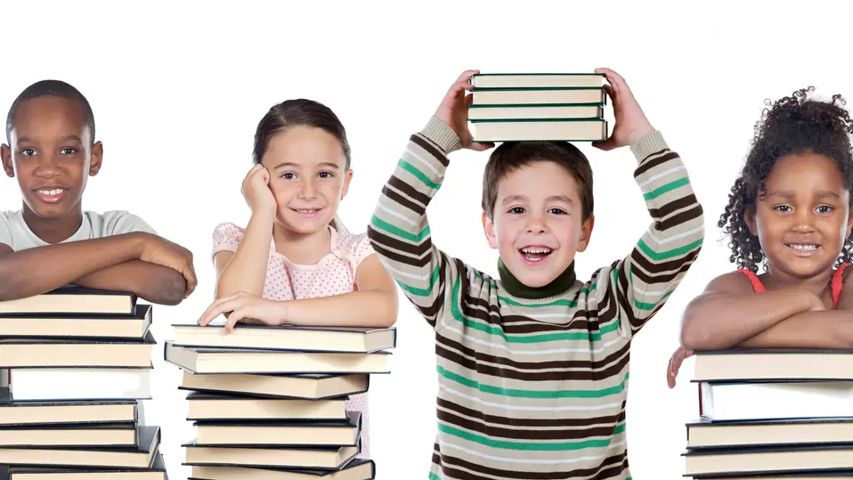Ett barn håller några böcker ovanför huvudet några andra barn lutar sig på några travar av böcker. De ser glada ut. Foto.